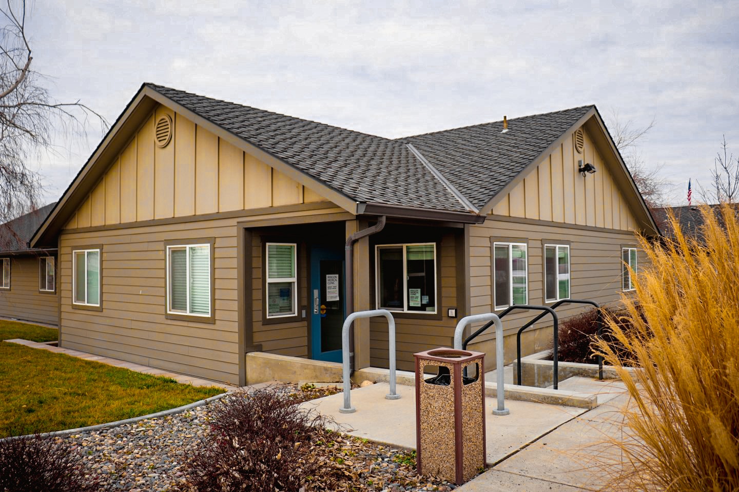 Single-story building with gabled roof, bike rack, and flagpole.