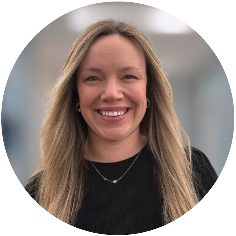 The image shows a woman with long blonde hair smiling, wearing a black top and a necklace, set against a blurred background.