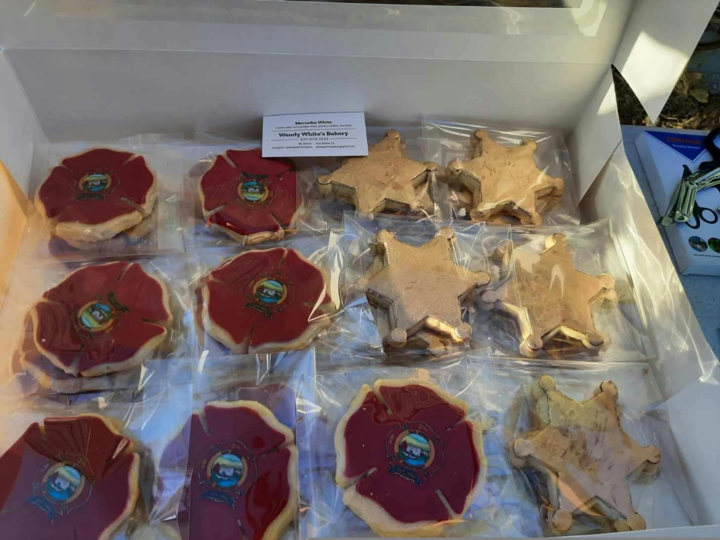 Boxes of cookies, some shaped like badges with frosting and an emblem, and others like characters, all individually packaged.