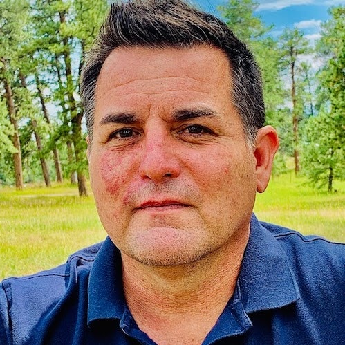 A man with a forest background.