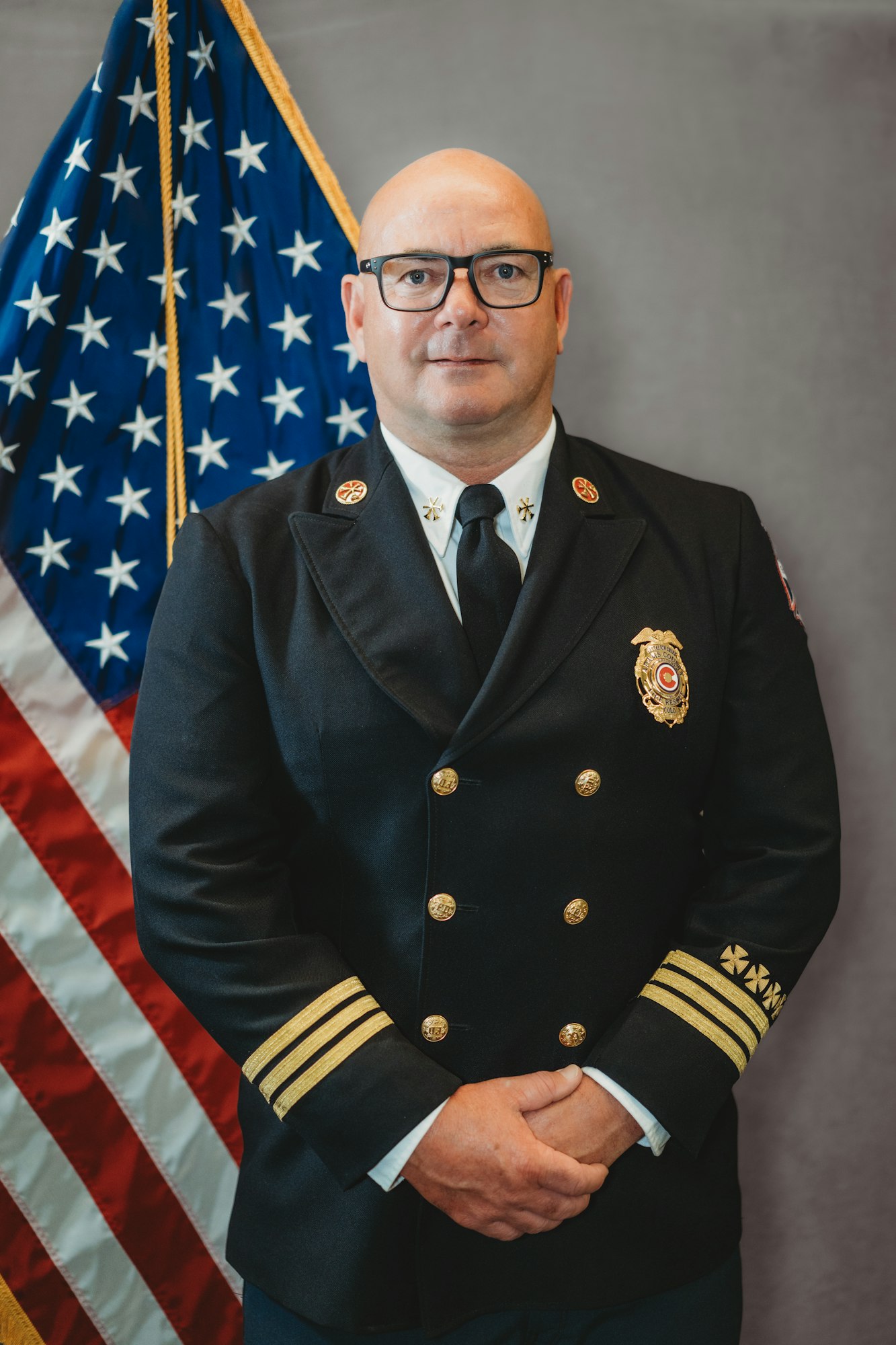 A person in a uniform with an American flag in the background.