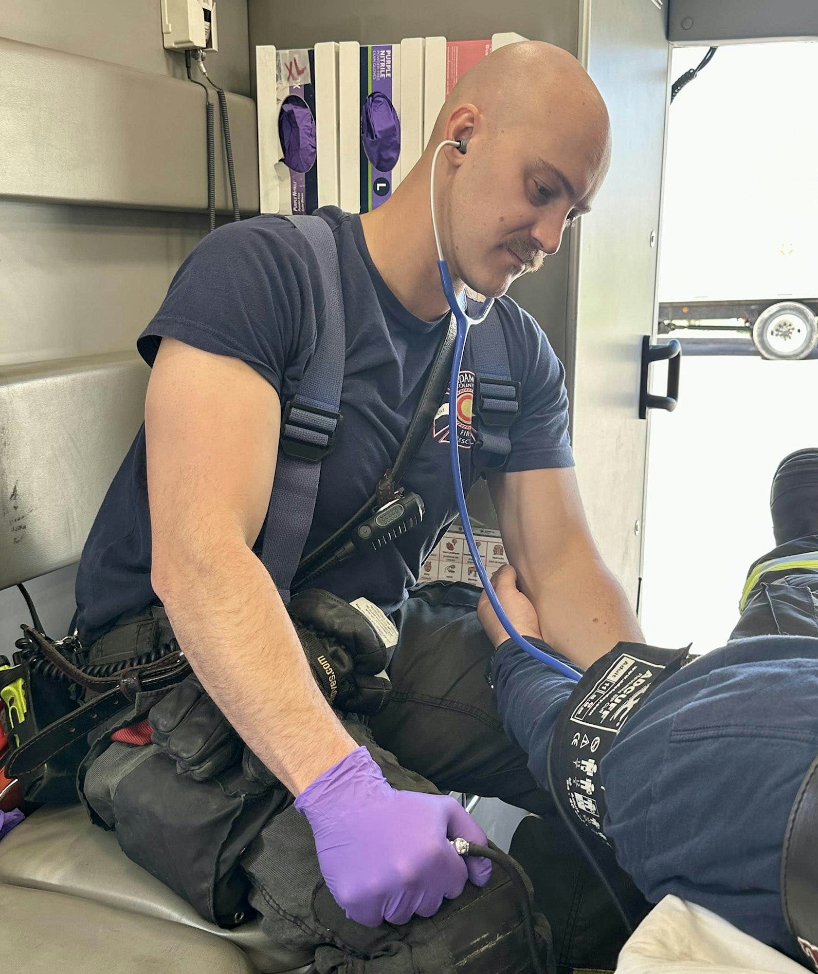A paramedic using a stethoscope to check a patient's blood pressure in an ambulance.