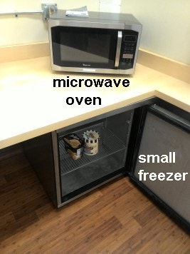 inside updated community building microwave on counter top and small freezer under counter in kitchen.