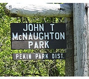 A sign for John T. McNaughton Park, located in the Pekin Park District, indicating the park's name and affiliation.