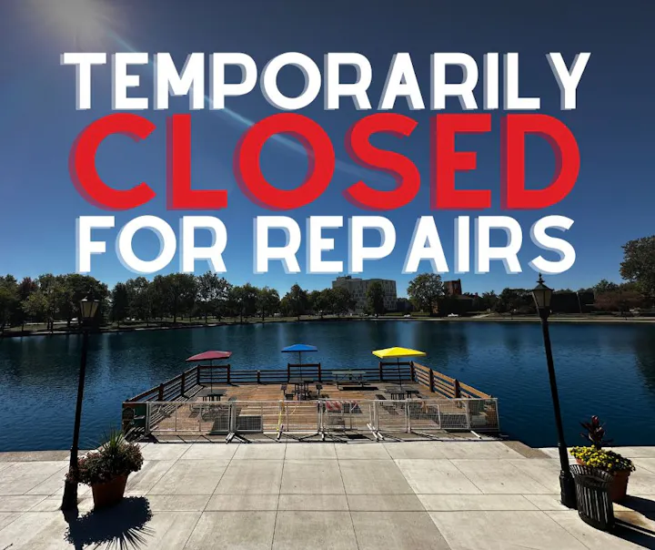 A scenic view of a dock by a lake, showing a sign that states it is "Temporarily Closed for Repairs."