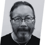 The image features a man with long hair and glasses, posing in a headshot.