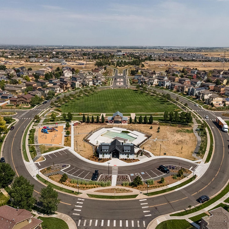 Aerial view of a suburban area with a park, circular road pattern, and houses.