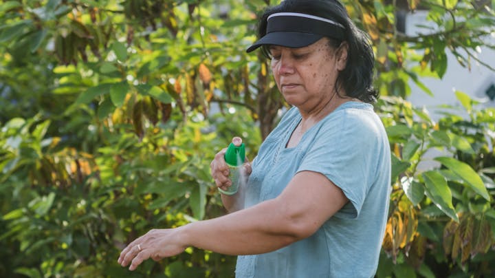 Woman applies mosquito repellent before her Memorial Day weekend plans.