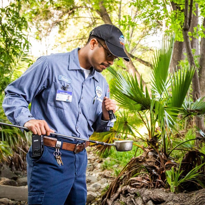 A security guard with a flashlight and keys in a natural setting, looking focused.