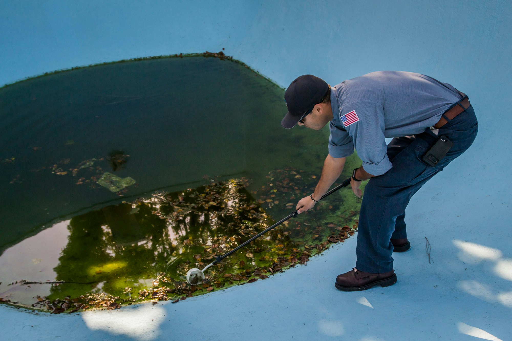 A person cleaning a pool with a net.