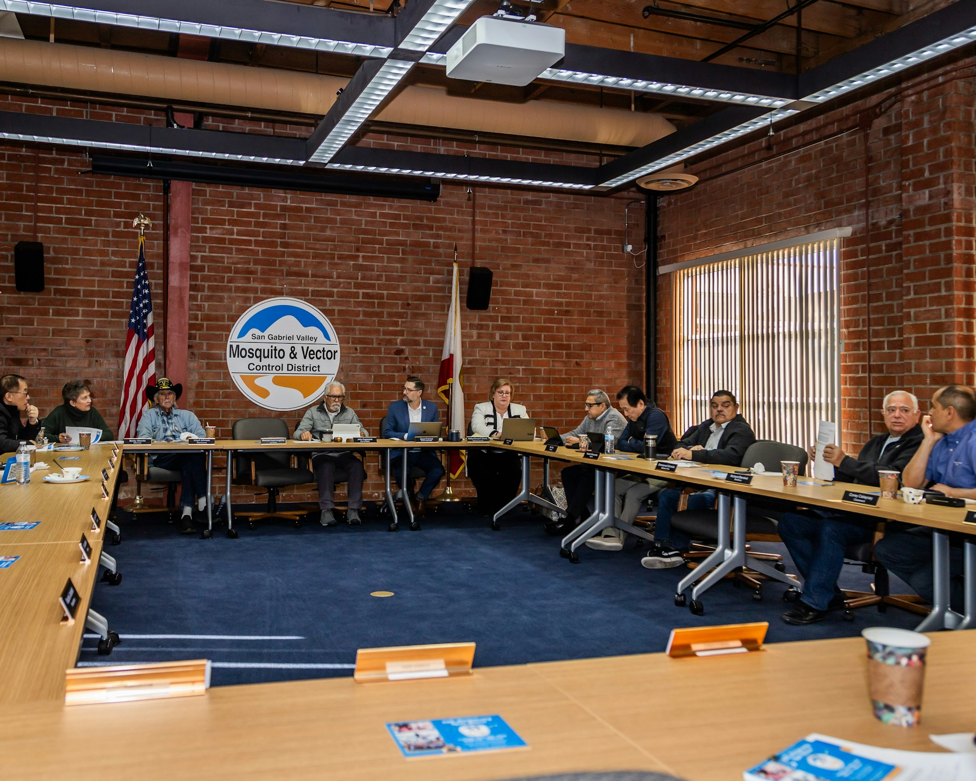 A group of people seated at a conference table in a brick-walled room with the San Gabriel Valley Mosquito & Vector Control District logo.