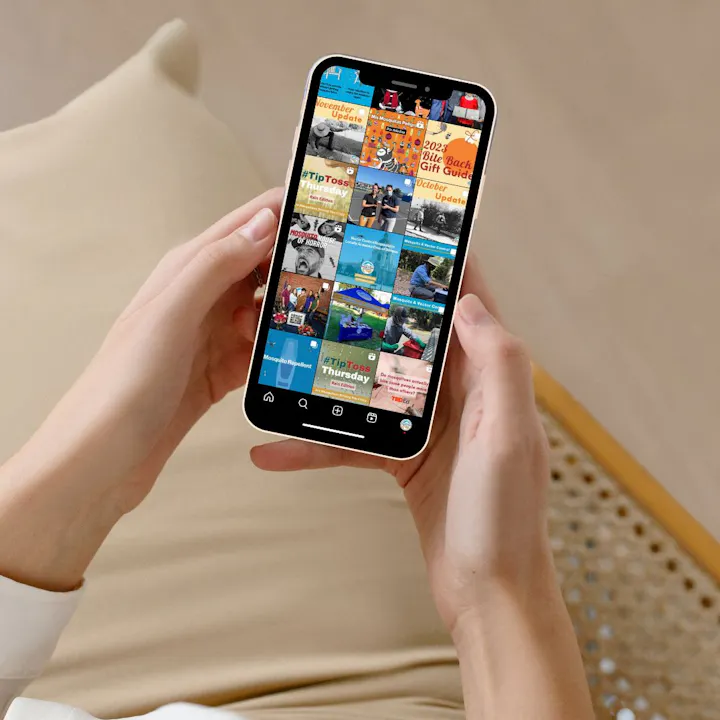 A person is holding a smartphone displaying a colorful grid of social media posts with various themes and updates.