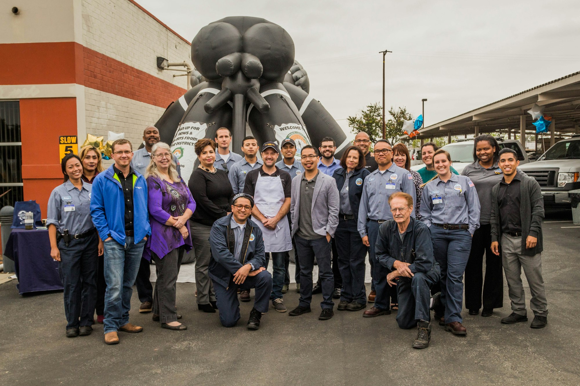A group of people smiling in front of an inflatable octopus at an outdoor event.