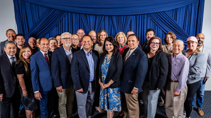 A group photo of a diverse gathering of individuals, smiling and posing together against a blue backdrop.