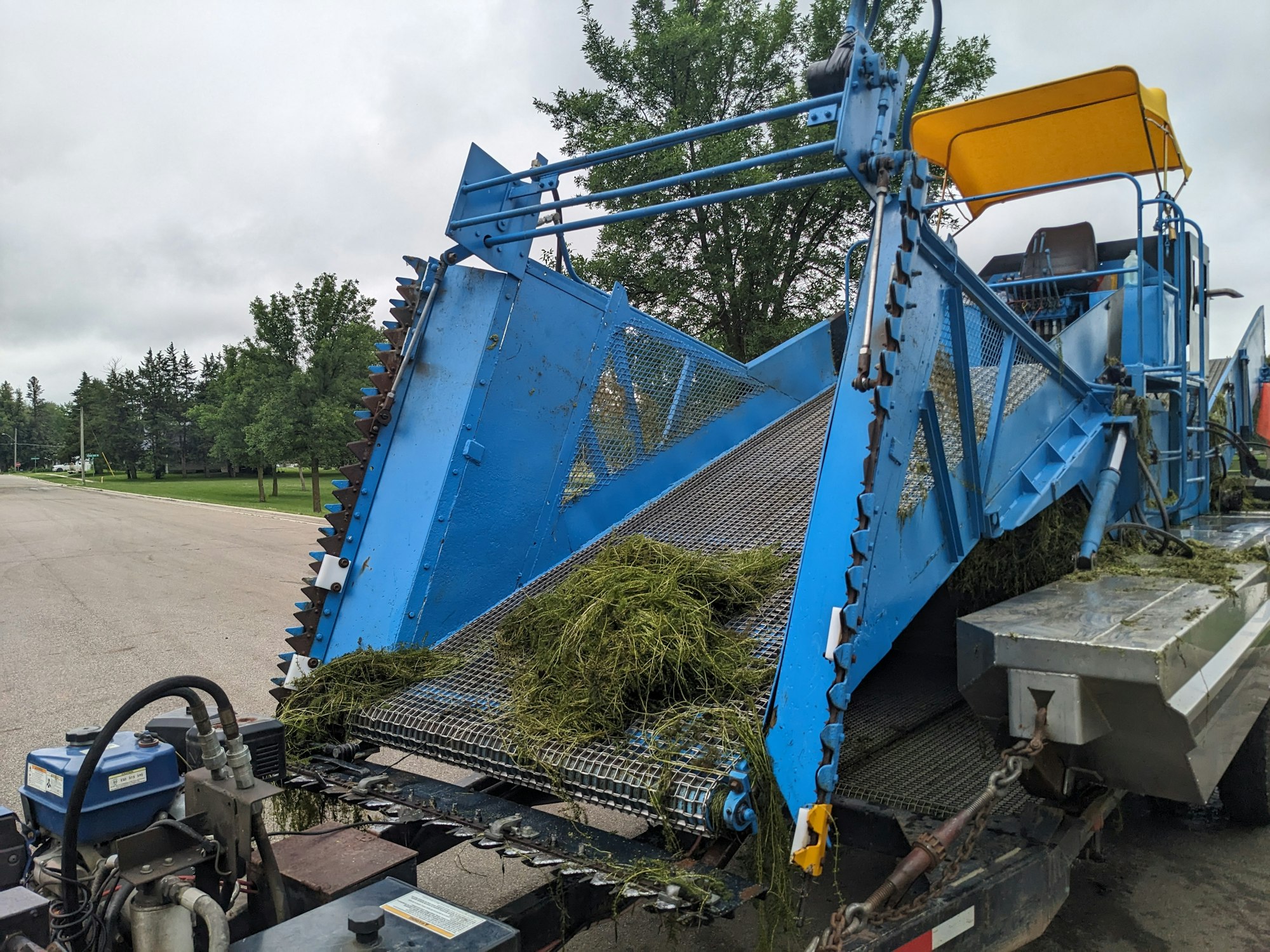 An industrial aquatic weed harvester with freshly collected vegetation.