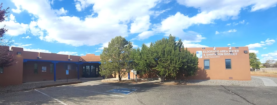A brown building labeled "Eldorado Area Water & Sanitation District" with trees, a parking area, and a partly cloudy sky.