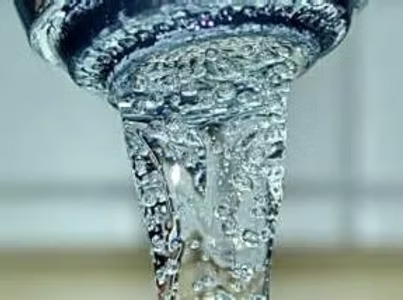 Water flowing from a faucet, captured in motion with visible bubbles.