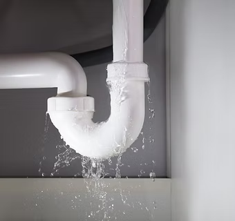 A leaking white PVC pipe with water dripping down.