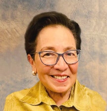 A person wearing glasses and a yellow shirt, smiling against a textured blue and beige background.