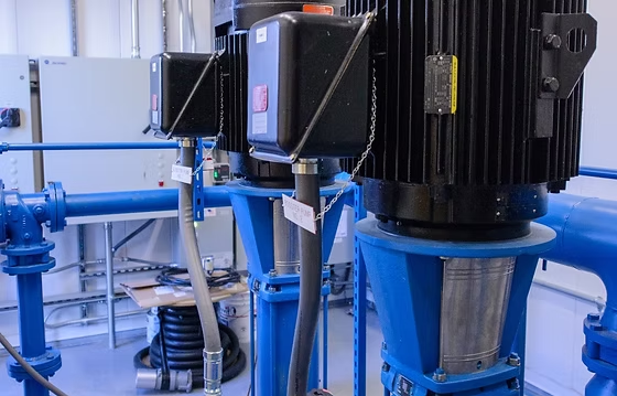 Industrial machinery with large electric motors, blue pipes, and control boxes in a facility.