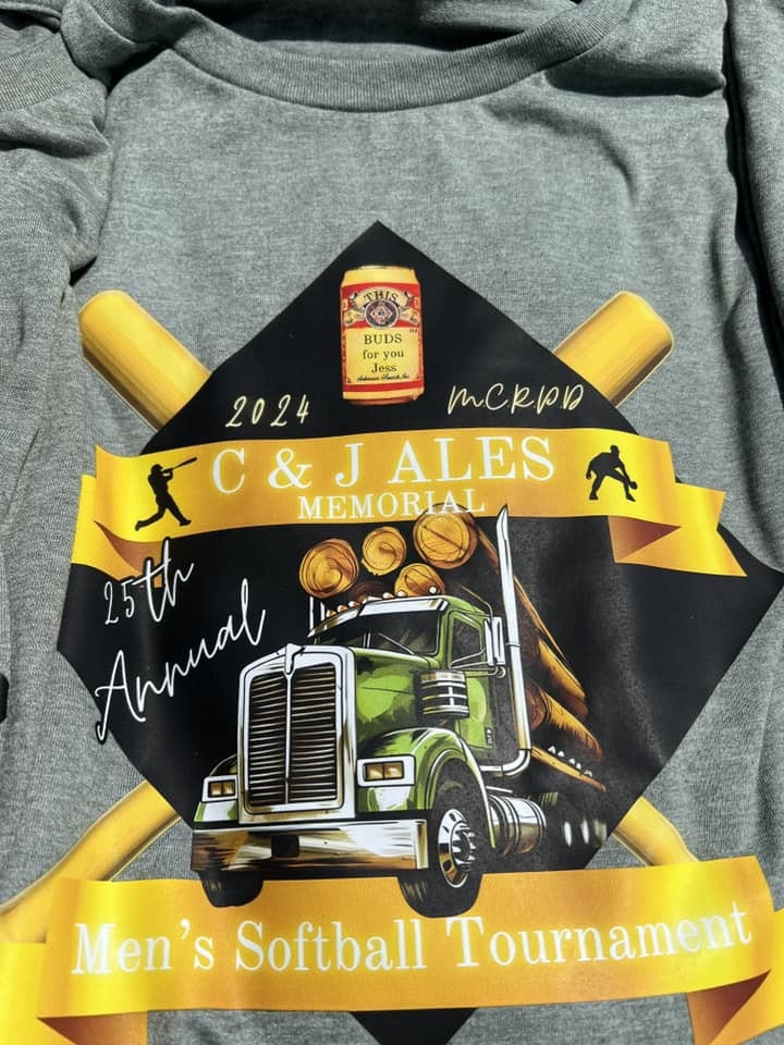 A t-shirt with a design for a memorial men's softball tournament featuring a truck and bats, dated 2024.