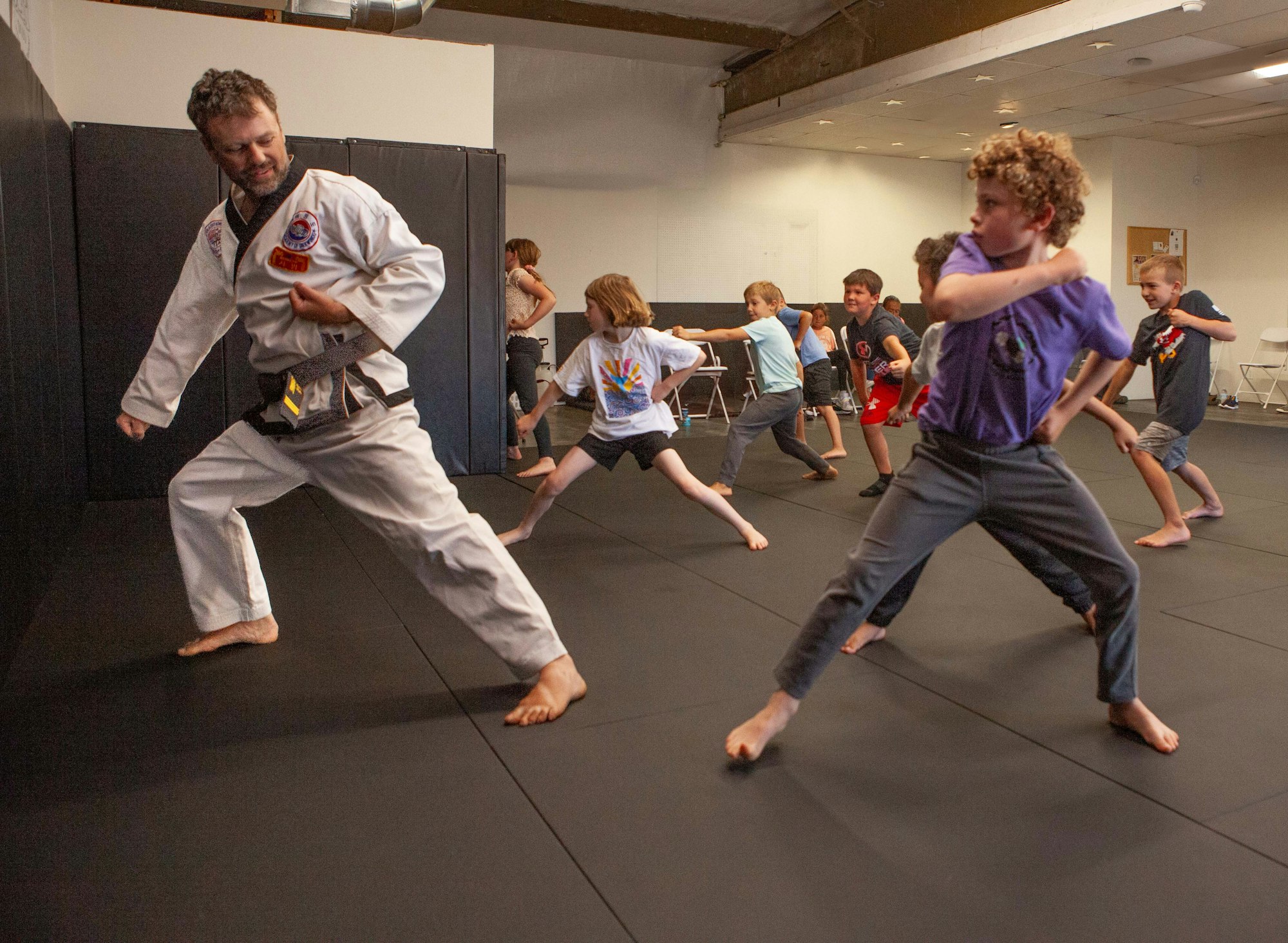 A martial arts class with a teacher and students practicing kicks.