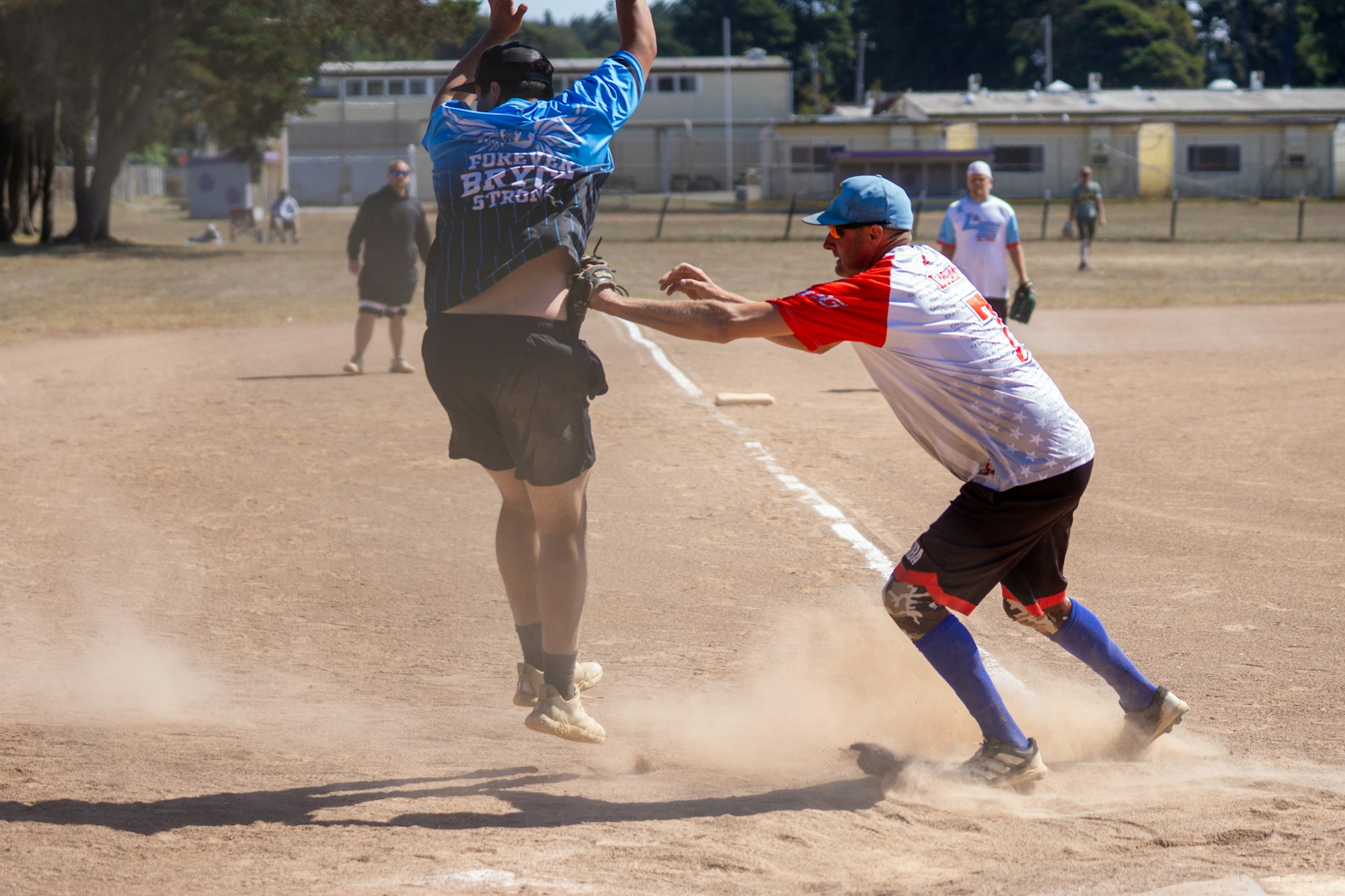 Two men in baseball outfits, with one tagging the other out as dust rises on a dirt field.