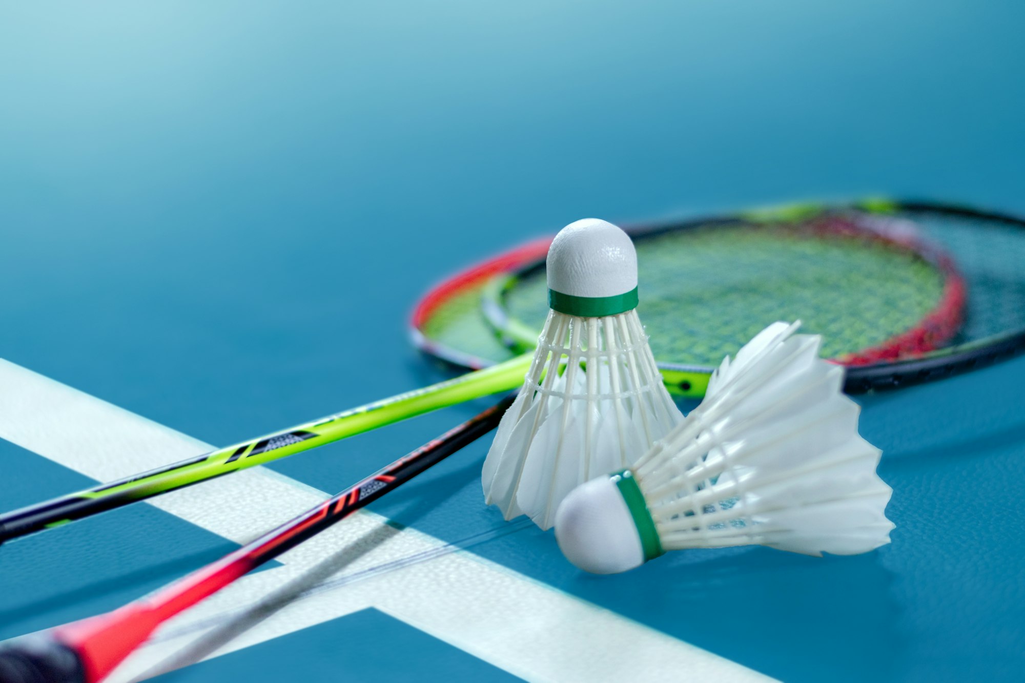 Badminton rackets and shuttlecocks on a court.