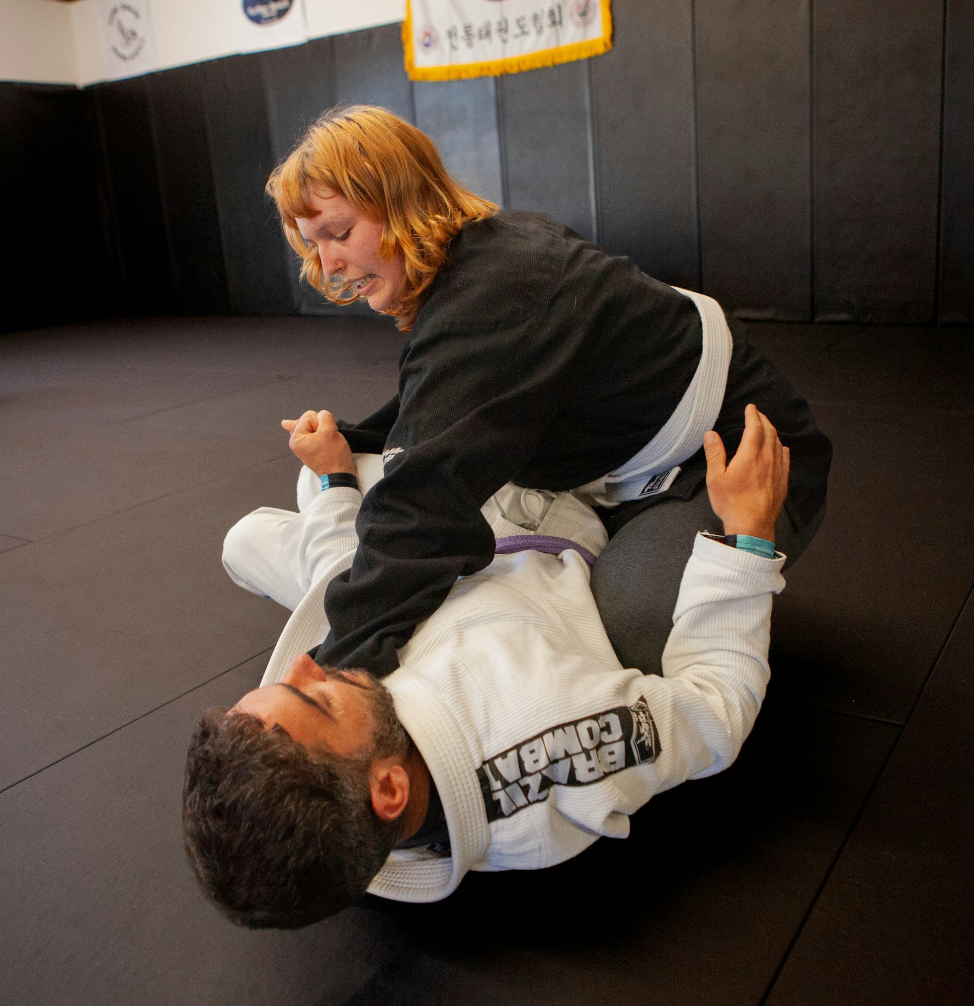 Two people practicing Brazilian Jiu-Jitsu on a mat, one executing a mount position on the other.