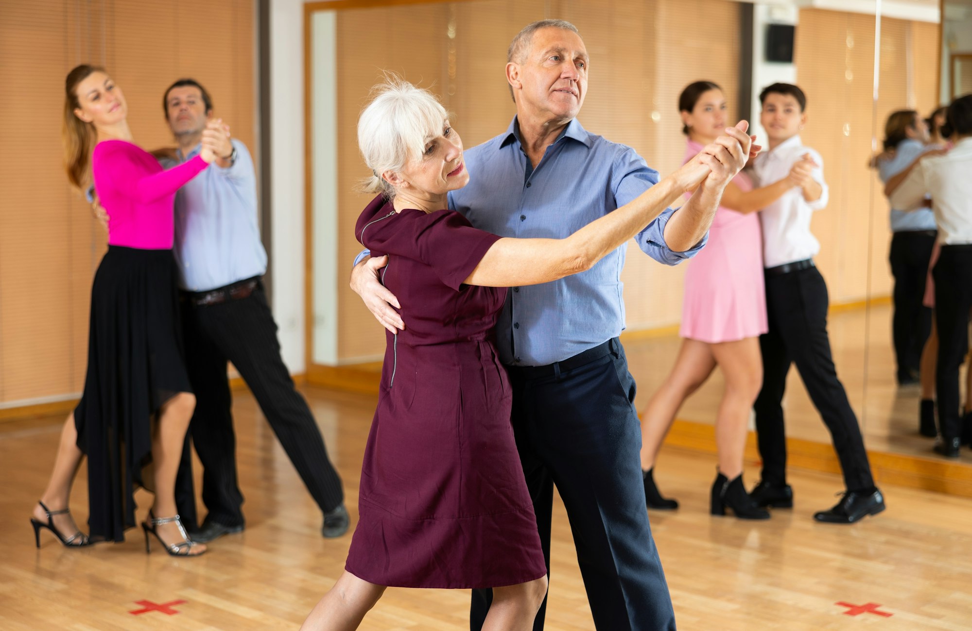 Couples dancing in a studio, practicing ballroom dance.