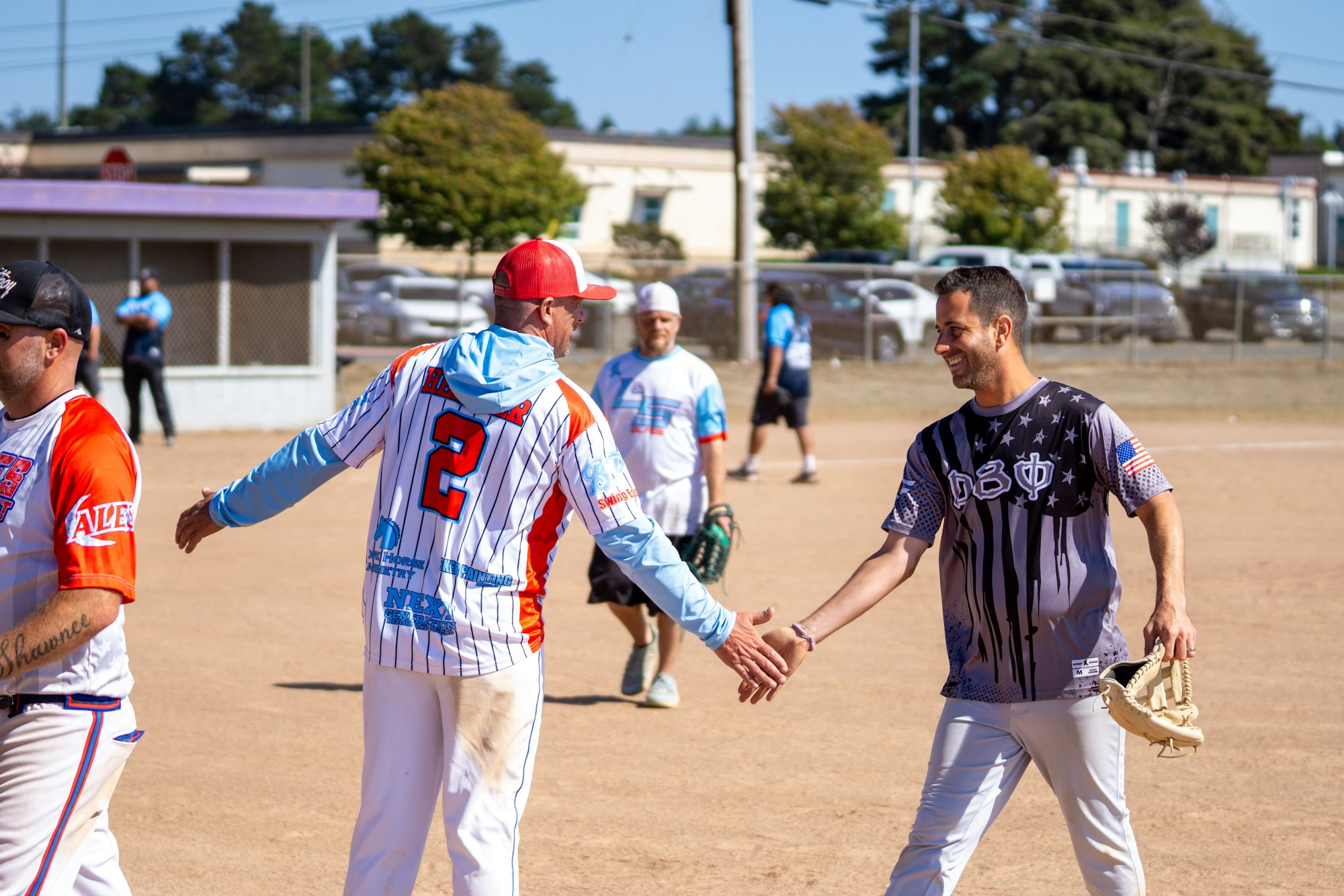 Two men in sports jerseys are shaking hands on a baseball field.