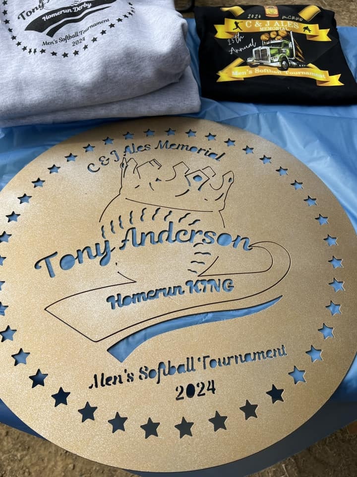 A golden trophy with the title "Homerun KING" for a 2024 Men's Softball Tournament, alongside event-themed shirts.