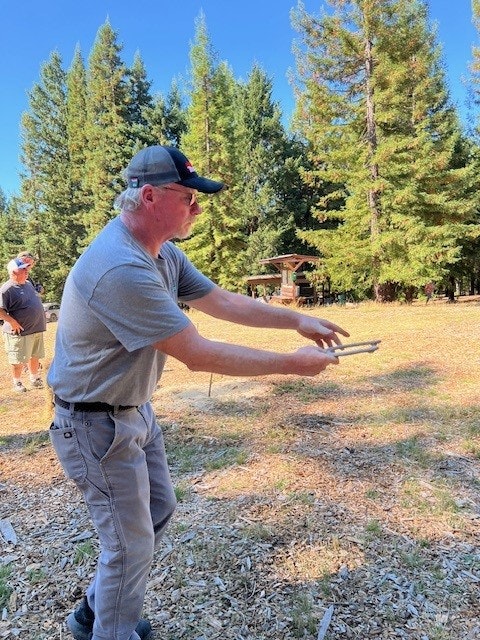 A man throwing a frisbee outdoors with trees in the background.