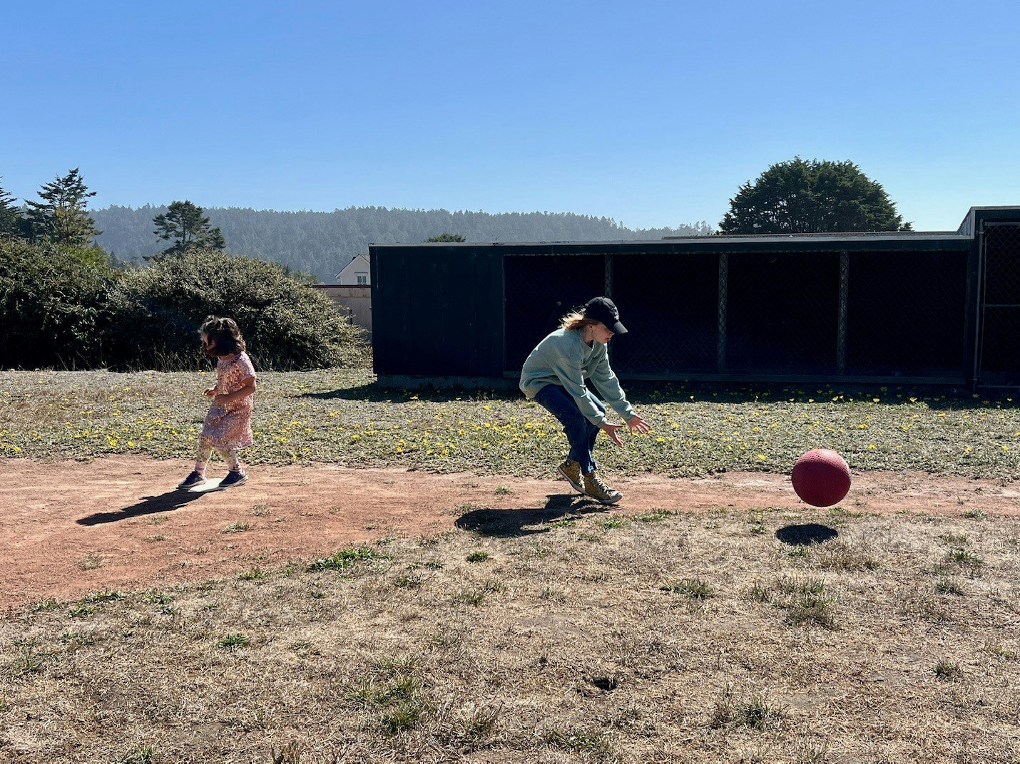Two people playing with a red ball outside.