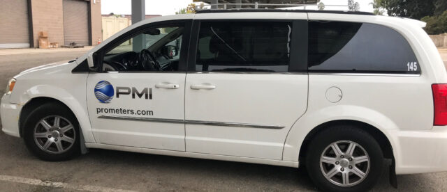 A white van with "PMI" and "prometers.com" on the side, parked in an industrial area.