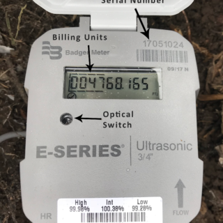 It's a water meter displaying usage, with a serial number, billing units, and an optical switch on the E-Series Ultrasonic model.