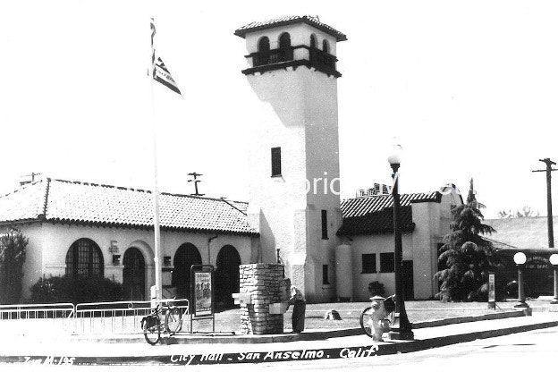 A historic black-and-white photograph of San Anselmo City Hall featuring a tower, trees, and a flagpole.