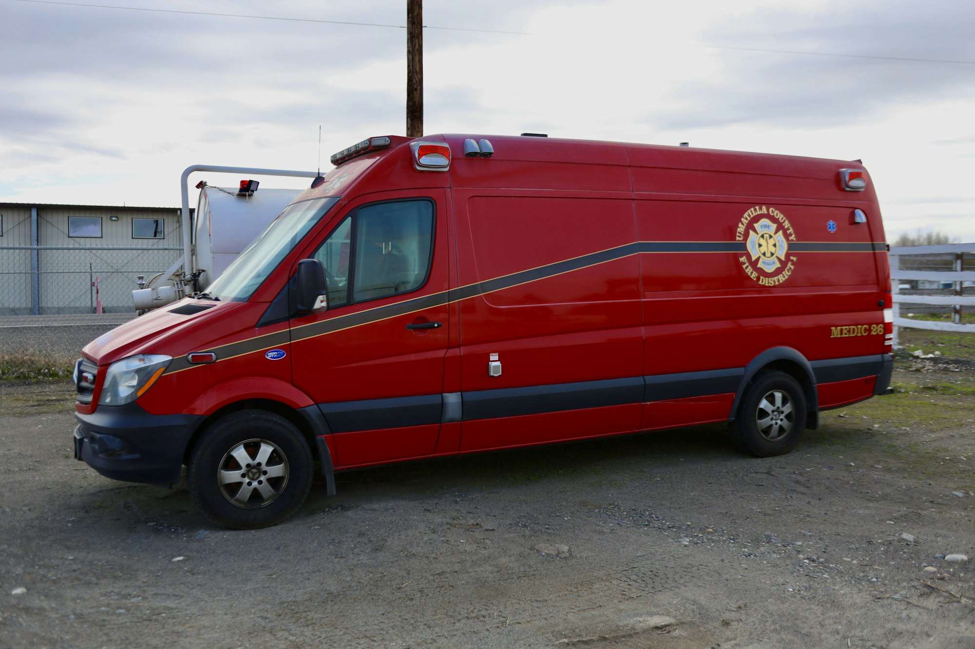 Red emergency response van with "Umatilla County Fire District 1" logo parked on gravel.