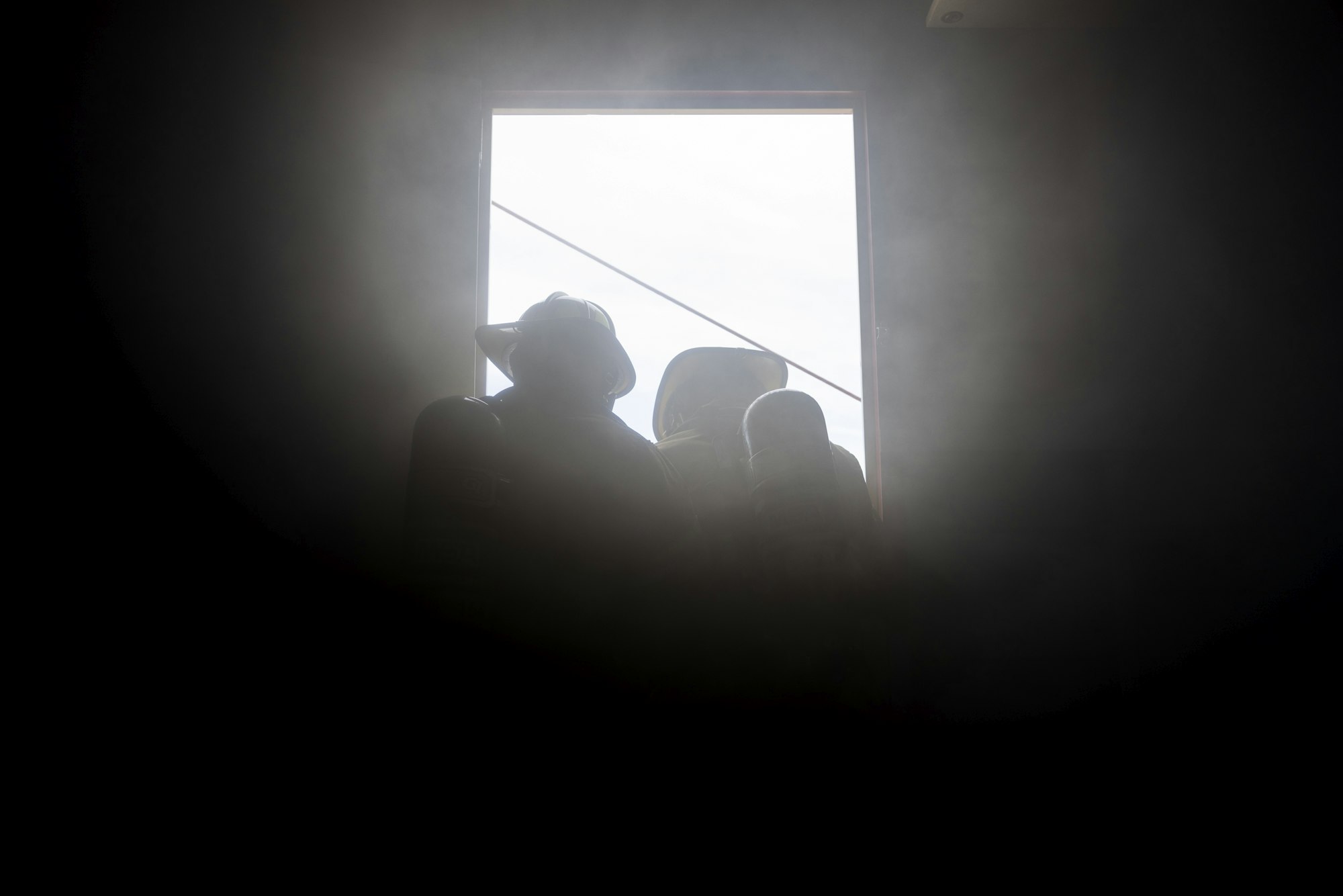 Silhouettes of people in hats through a window, with a smoky or misty background.