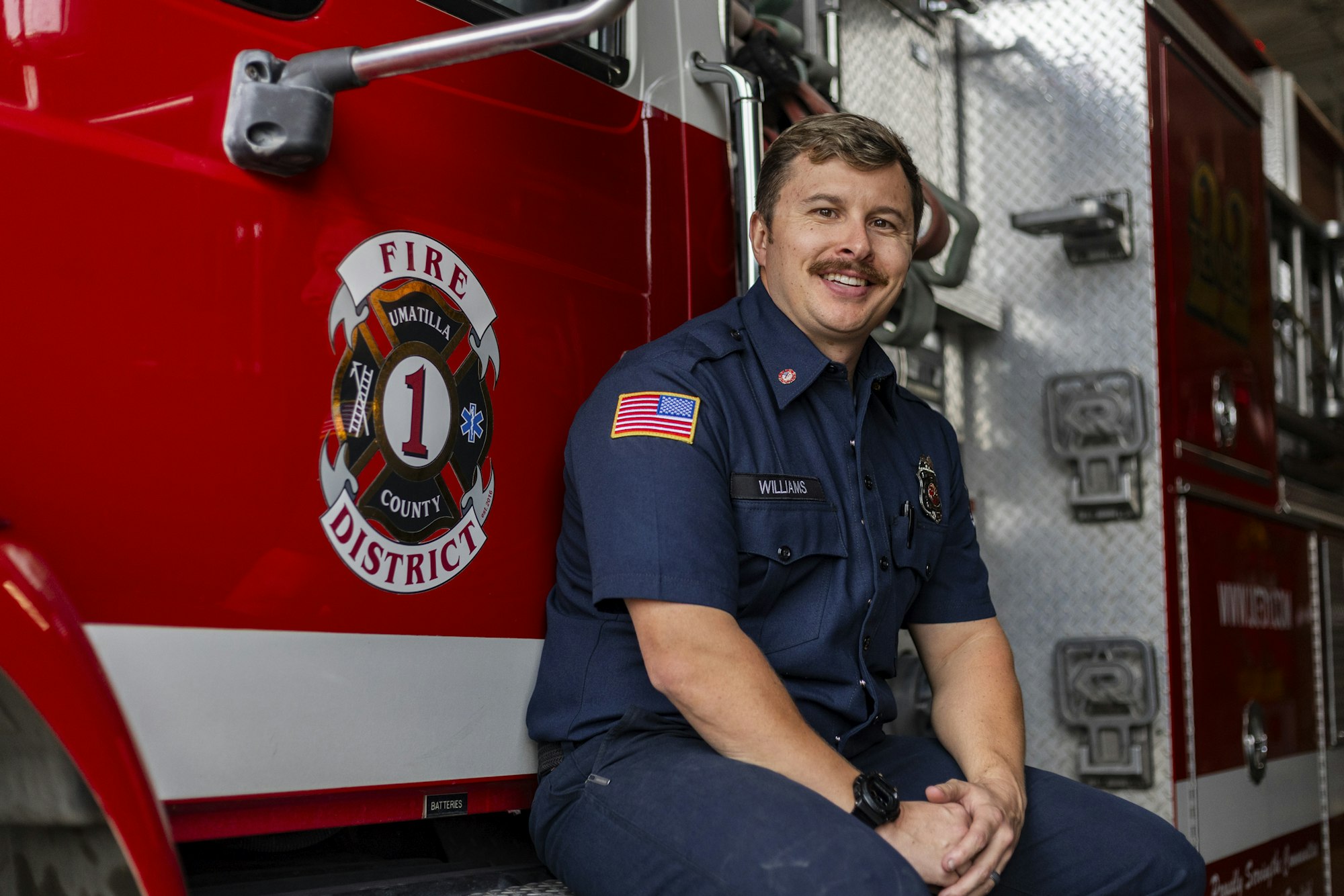 Firefighter in uniform sitting on a fire truck from Umatilla County Fire District 1.