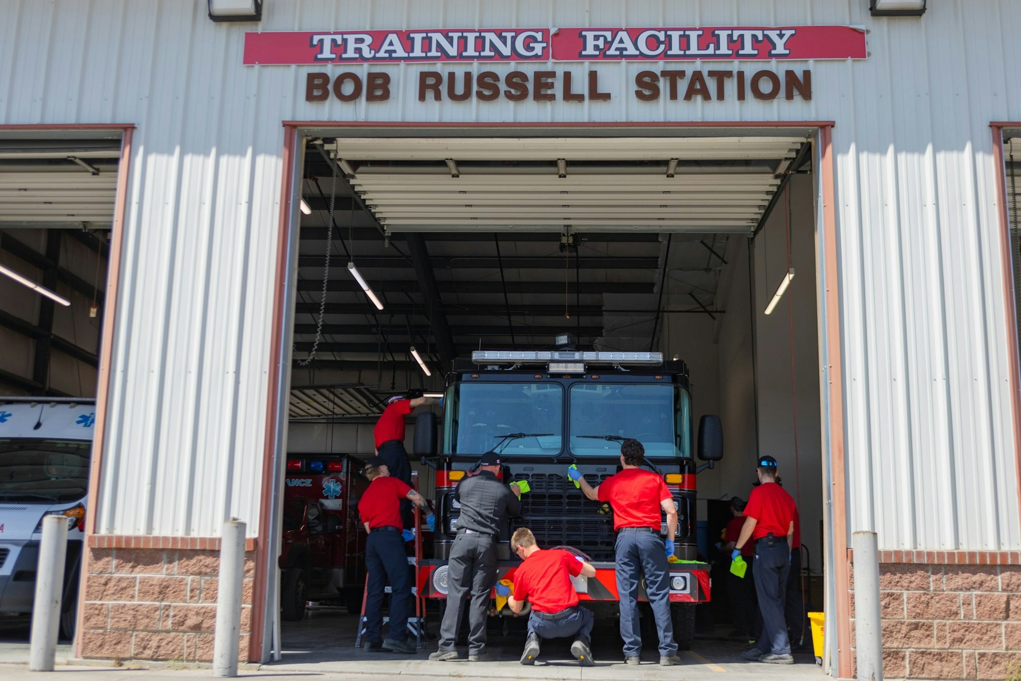 May contain: clothing, footwear, shoe, person, adult, male, man, glove, accessories, bag, handbag, fire truck, transportation, truck, vehicle, hat, and fire station