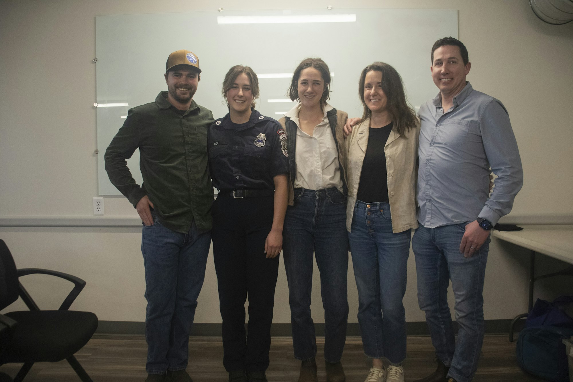 Five people standing together, smiling. One is in a uniform.