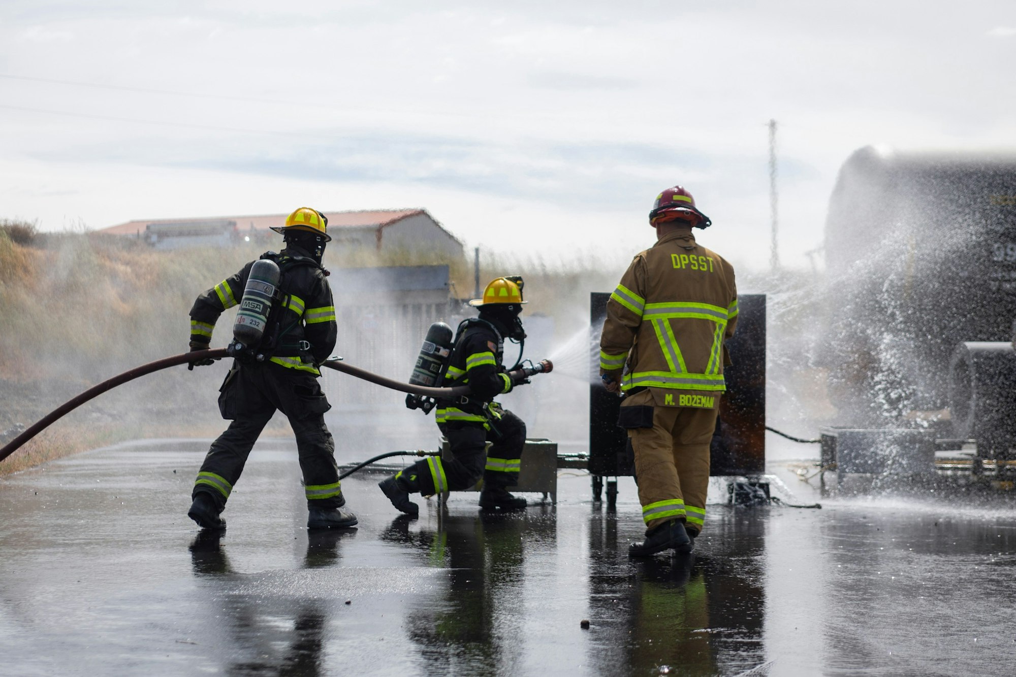 Firefighters in gear, using hoses to spray water, managing a fire emergency outdoors.