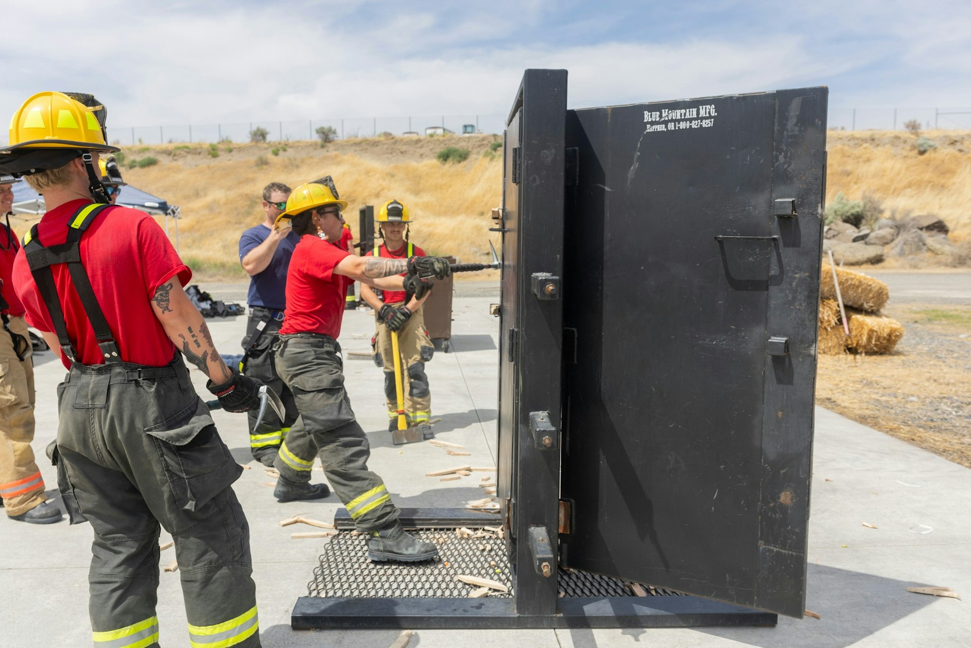 Firefighters practice using a forcible entry door training prop outdoors.