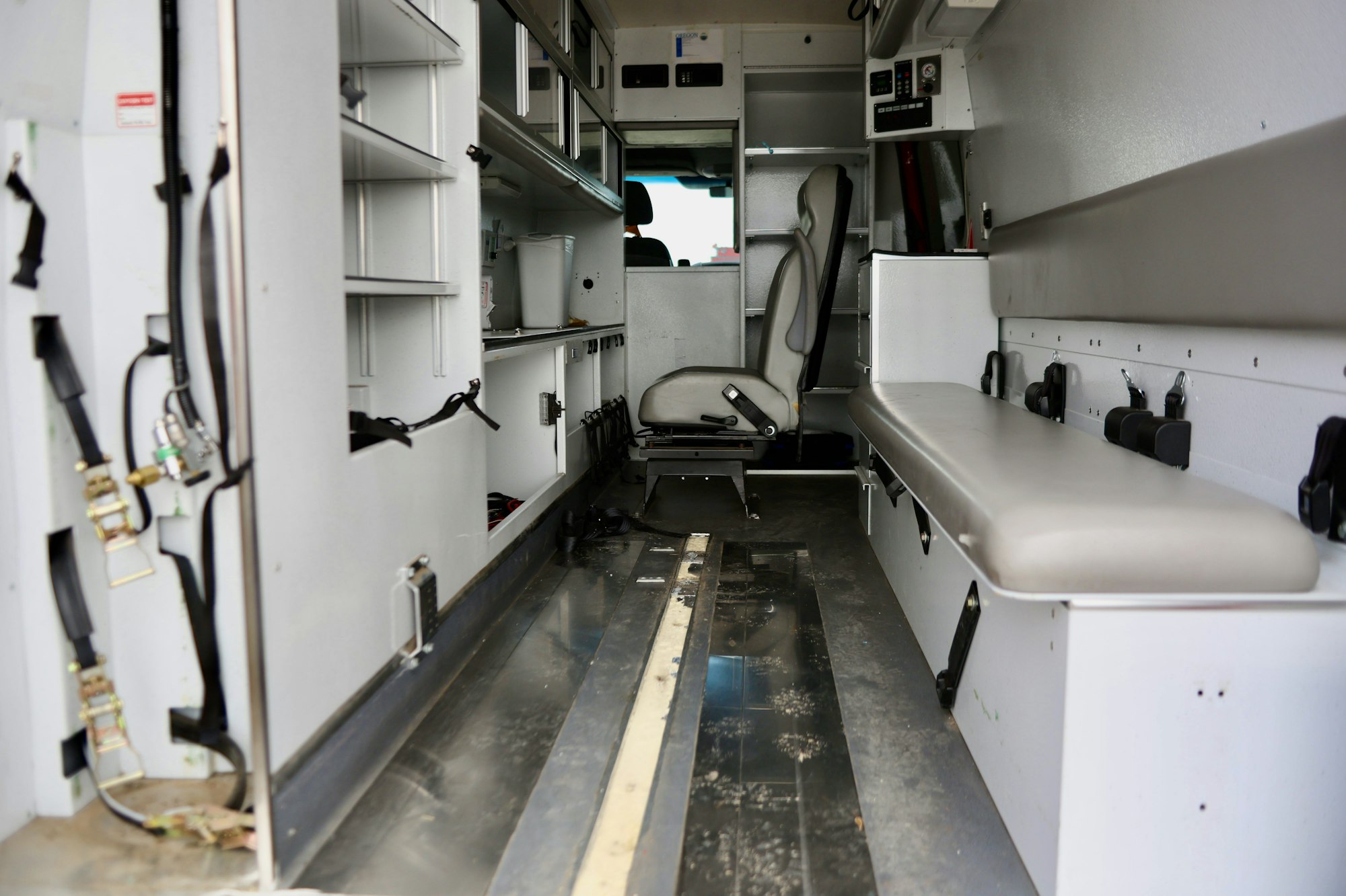 Interior of an empty ambulance with seats and medical equipment compartments.