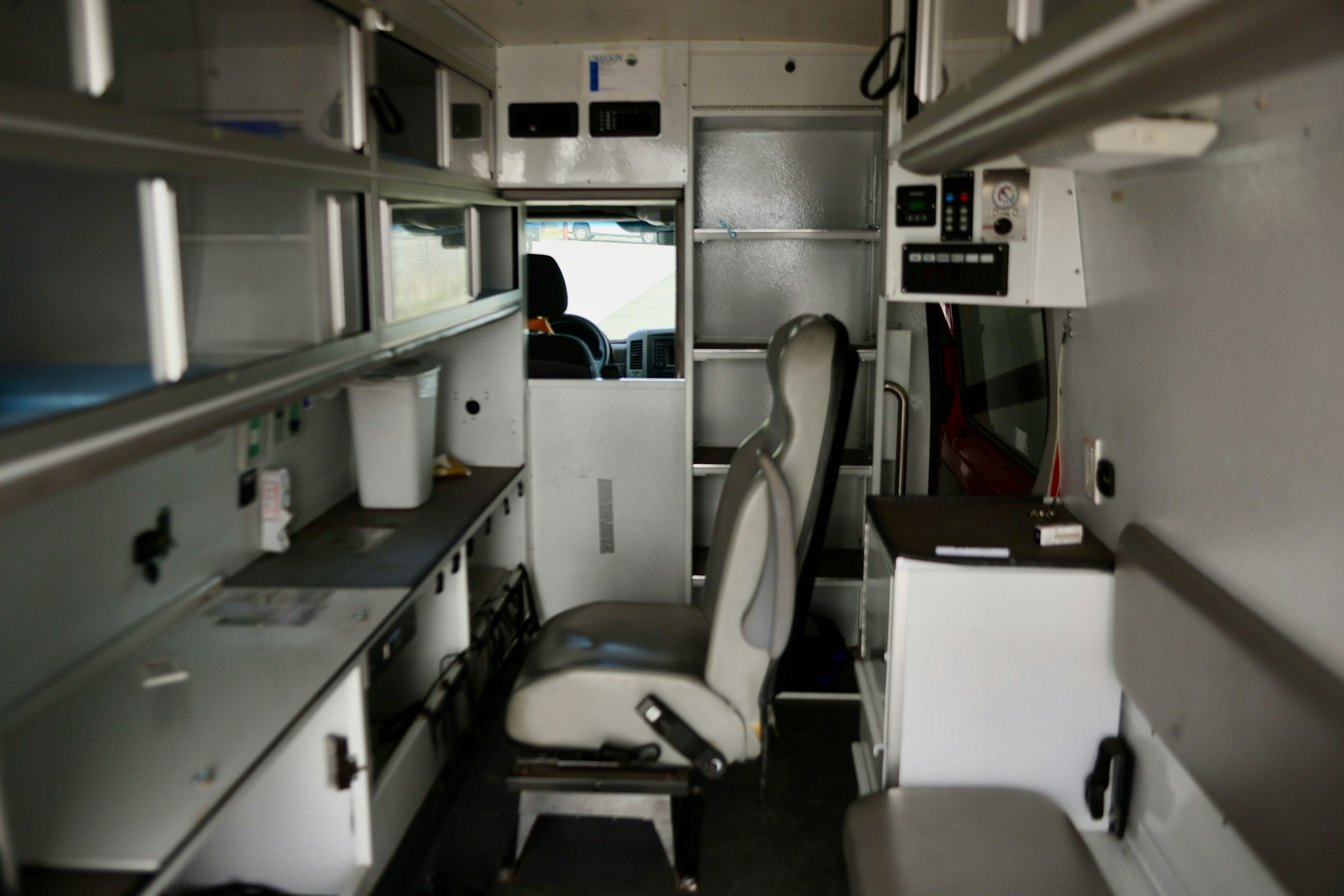 Interior of an ambulance showing seats, cabinets, and medical equipment.