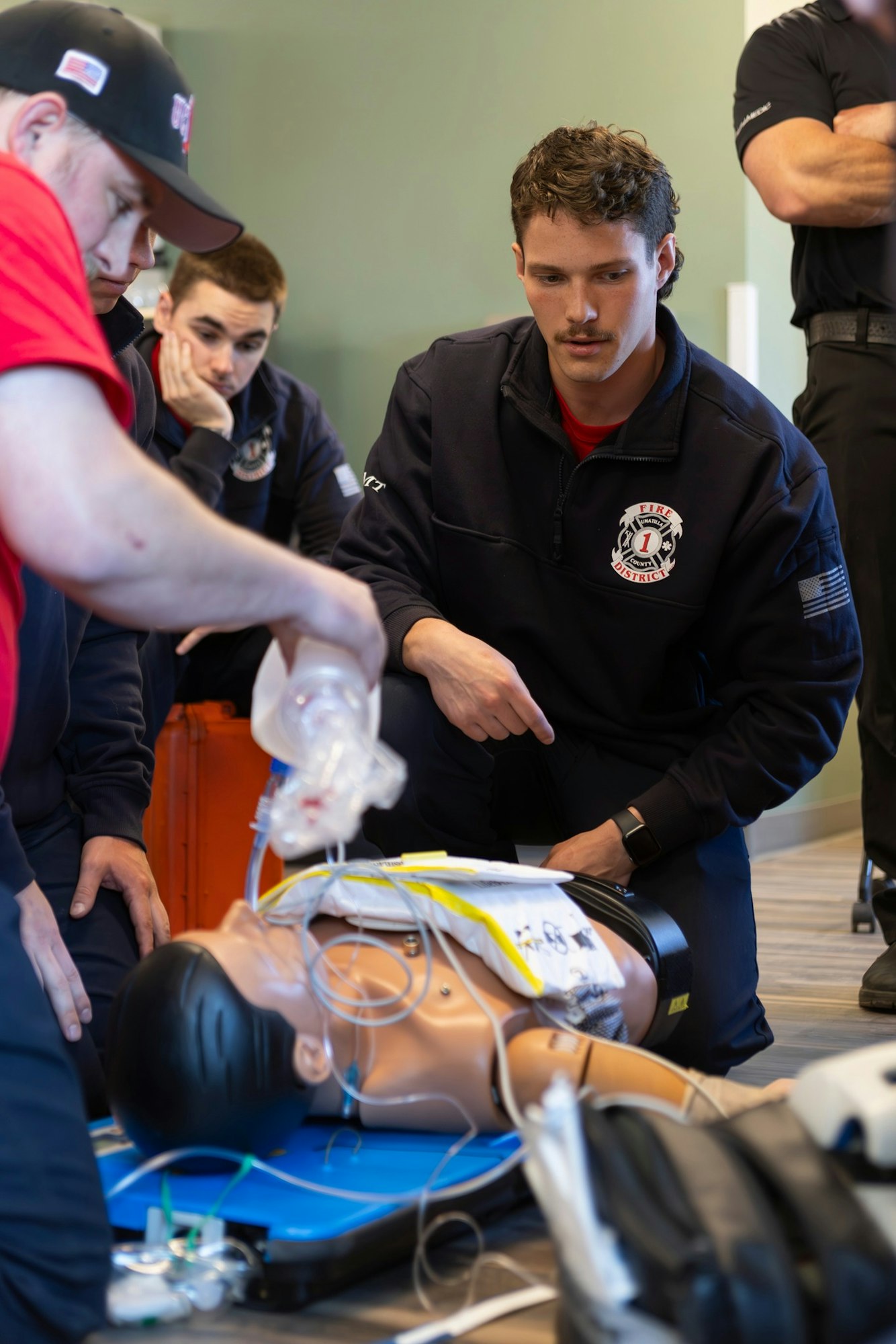 Group of medics practicing emergency procedures on a medical dummy using an oxygen bag.