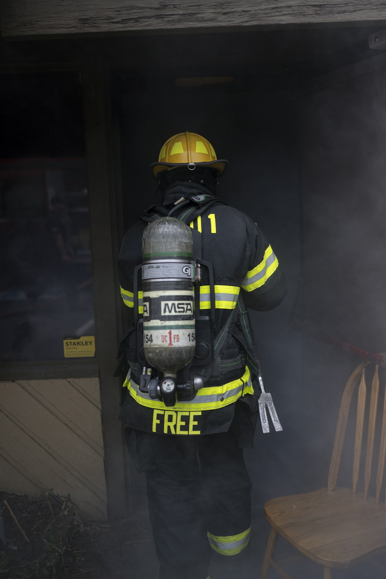 A firefighter in gear entering a smoky area, wearing a helmet and oxygen tank.