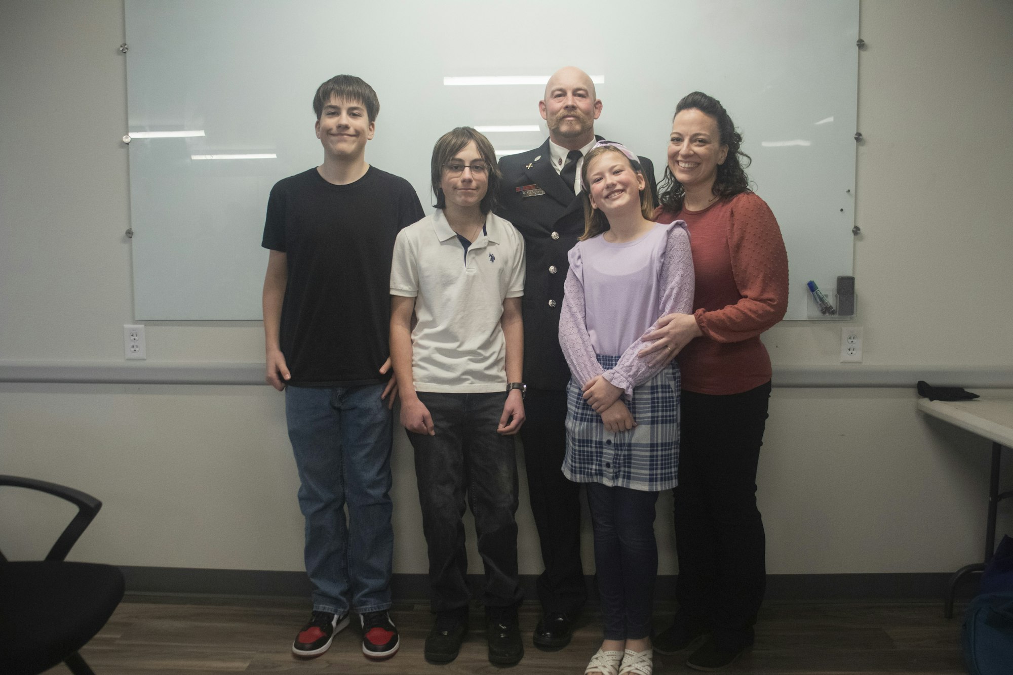 A group of five people posing together indoors, with one in a uniform.
