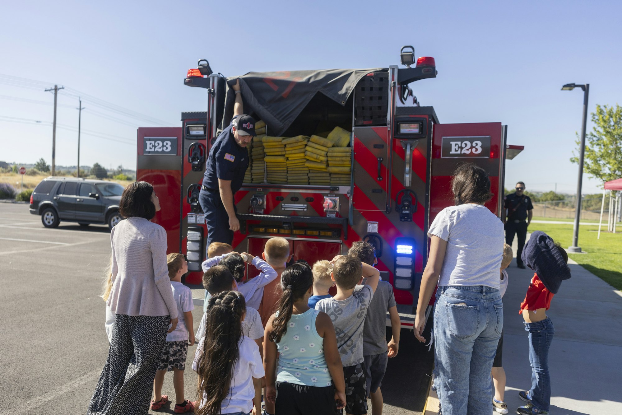 A firefighter shows kids a fire truck and equipment.